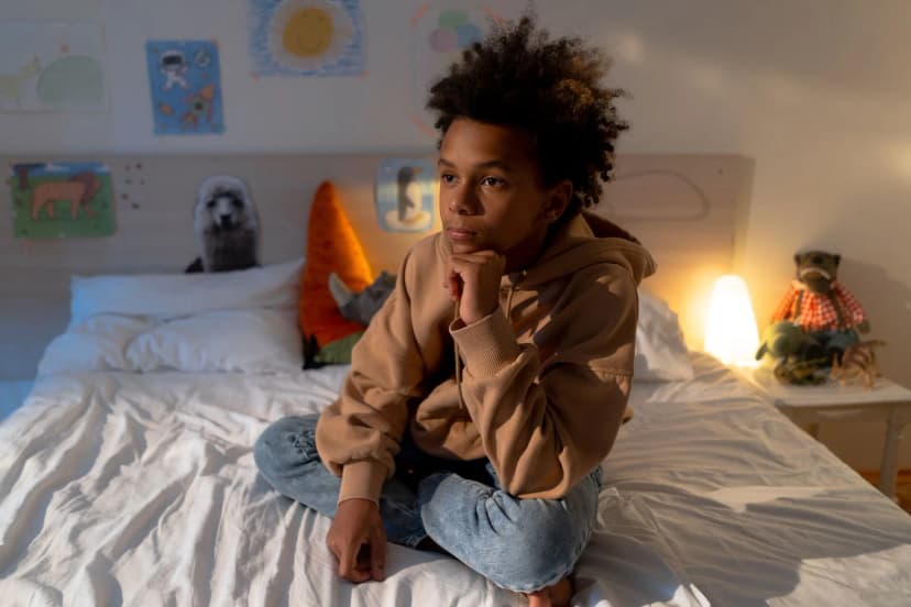Teen sitting alone on their bed, a common moment when a teen refuses therapy Teen sitting alone on their bed, a common moment when a teen refuses therapy